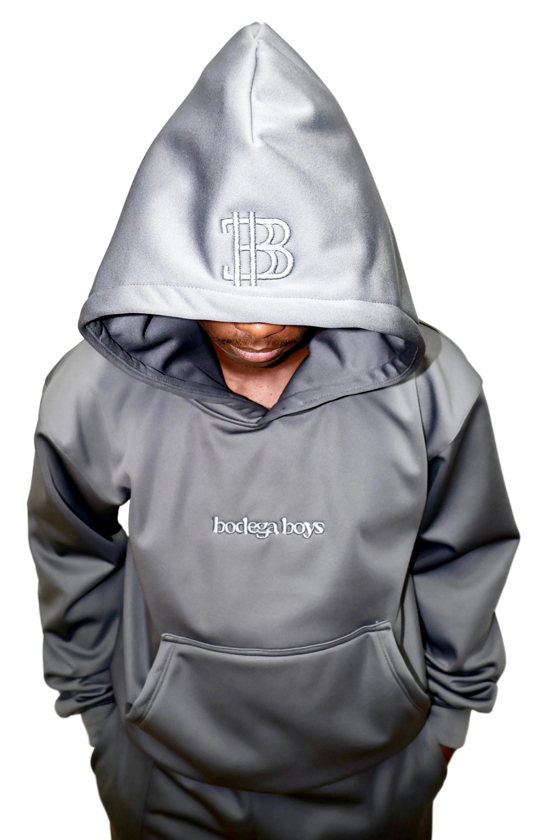 Person wearing a gray hoodie with a logo and text on a plain background