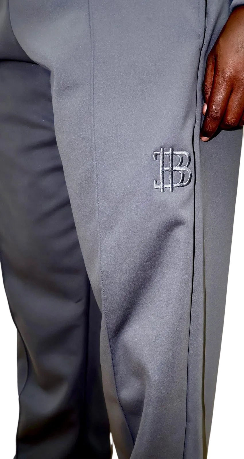Gray pants with a logo on the side, worn by a person.