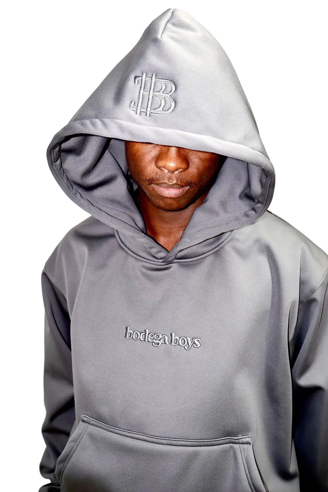 Person wearing a gray hoodie with text on the hood and front, against a plain background